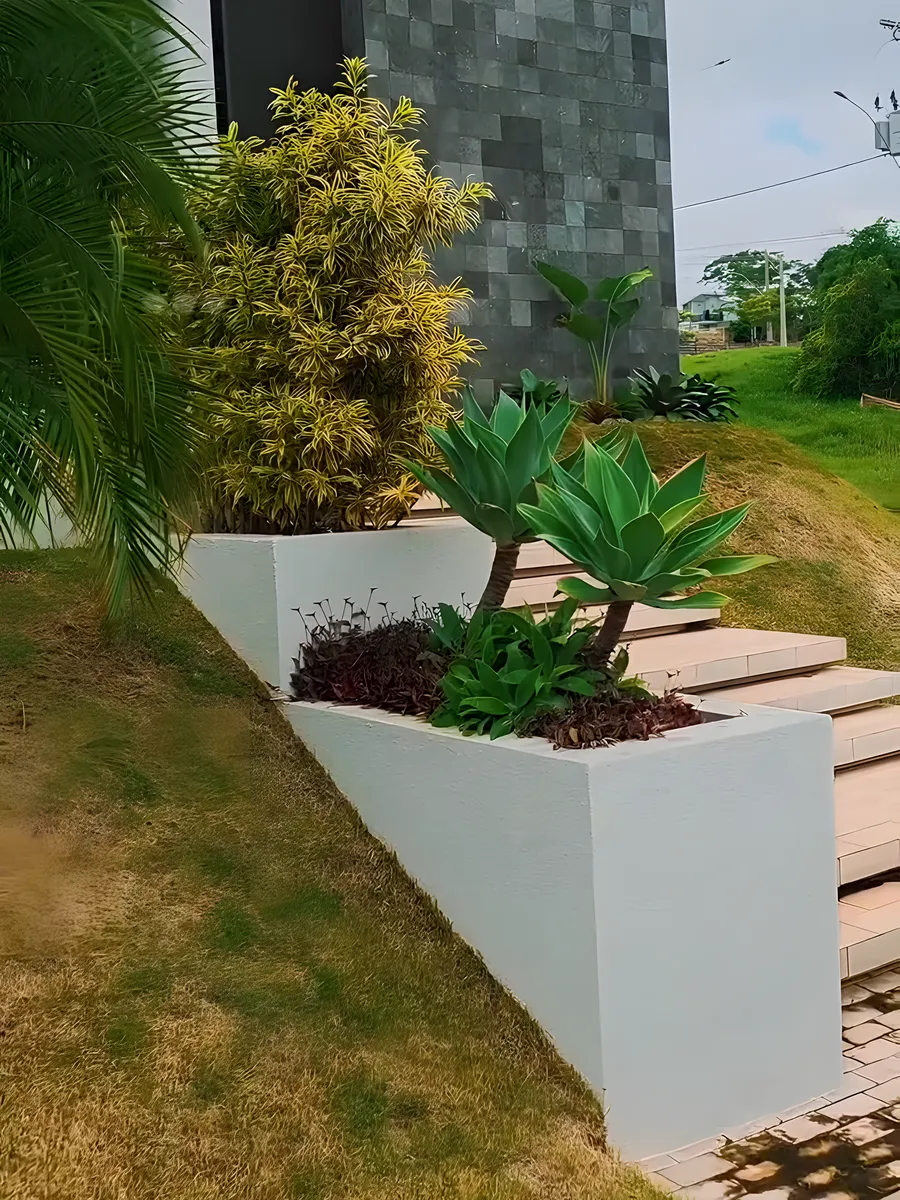 Jardineiras brancas com plantas na rampa de acesso de uma casa no Damha Belvedere